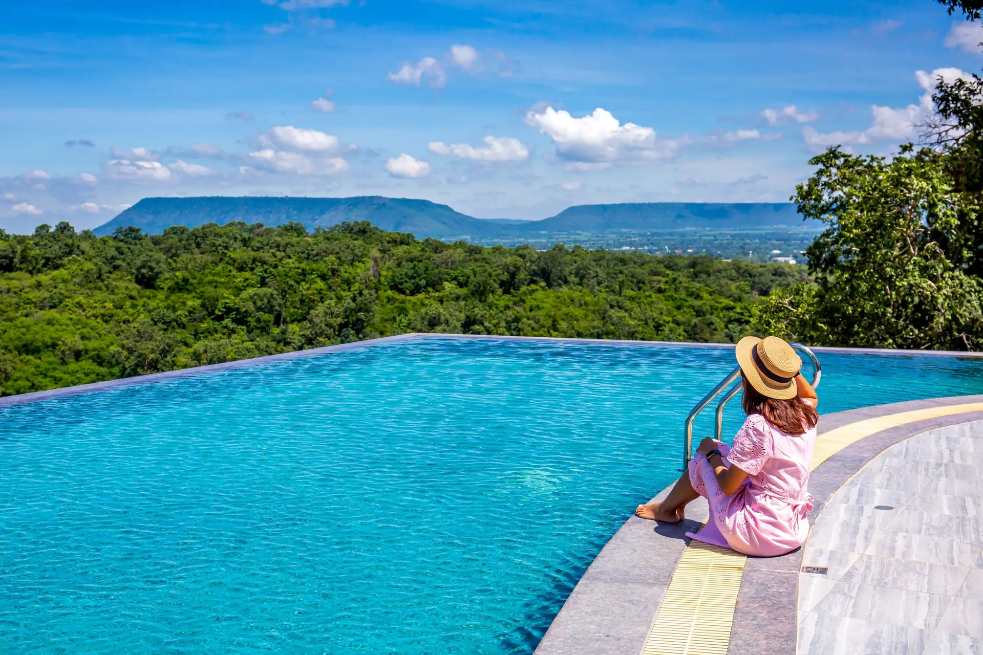 A guest sitting at the edge of the Sky Pool under a blue sky